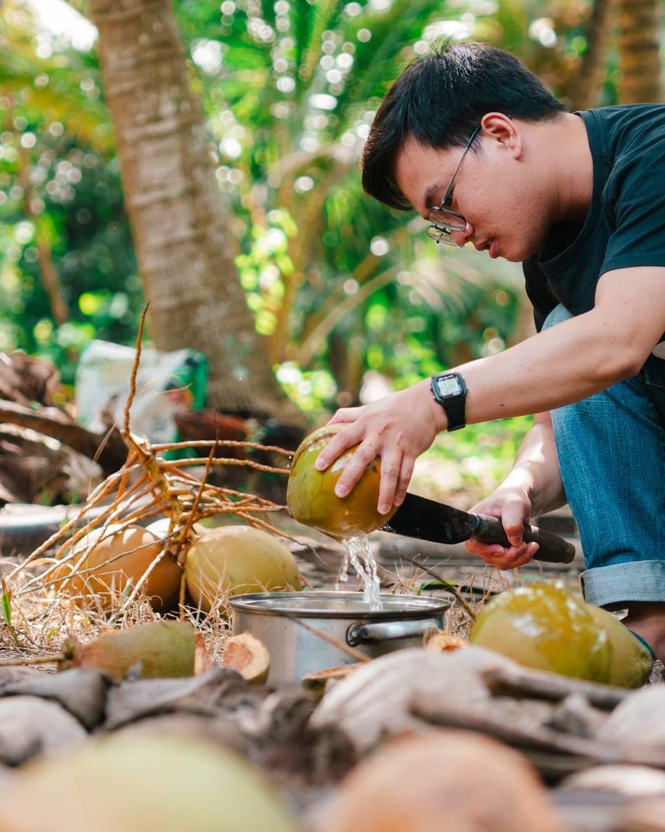 A grower opening a freshly harvested coconut by hand at a smallholding