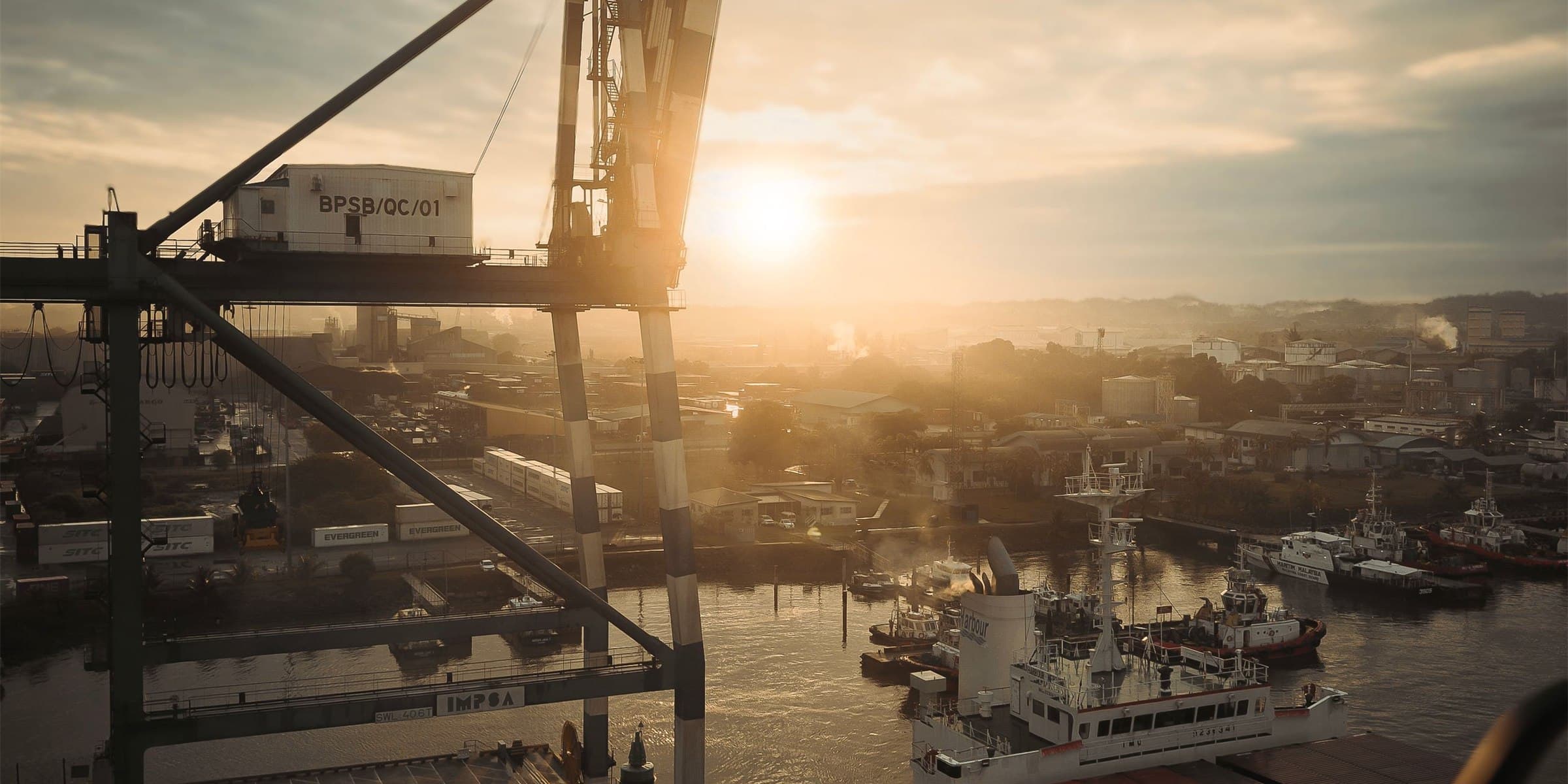 A harbour gantry crane silhouetted against a low sun